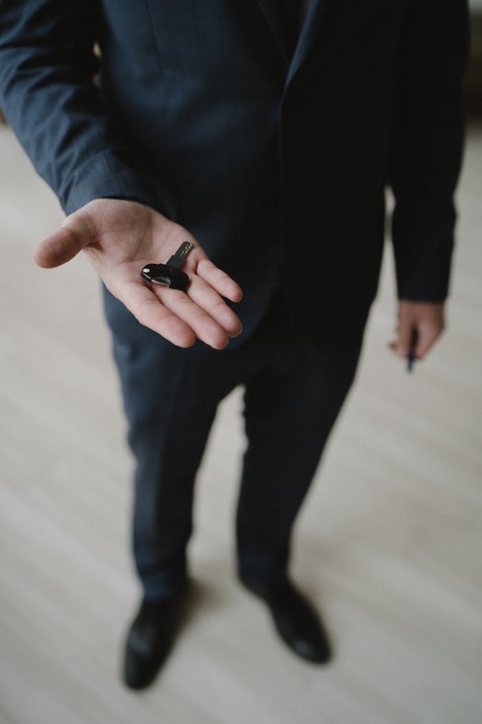 Close-up of a businessman in a suit holding car keys, inviting gesture.